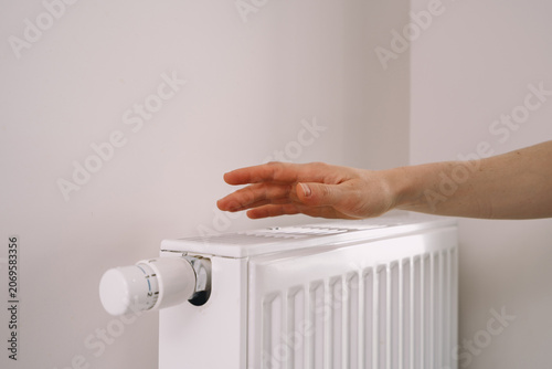 Φωτογραφία Hand checks warmth of home heating radiator in modern apartment