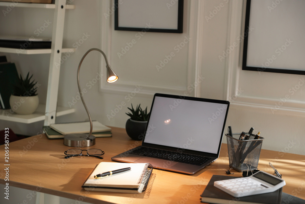 Fototapeta premium Stylish workplace with lamp, laptop and stationery indoors