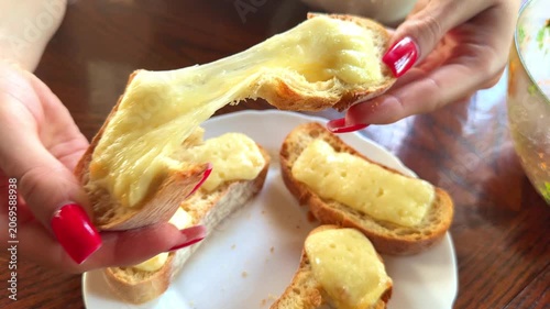 A woman breaks up crispy white bread baked with cheese with her hands