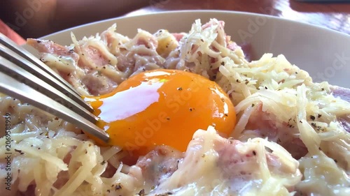 Close-up of a runny egg yolk in carbonara pasta