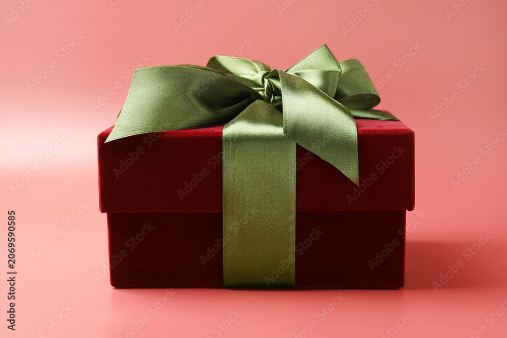 Fototapeta premium Gift box with green satin bow on red background, closeup