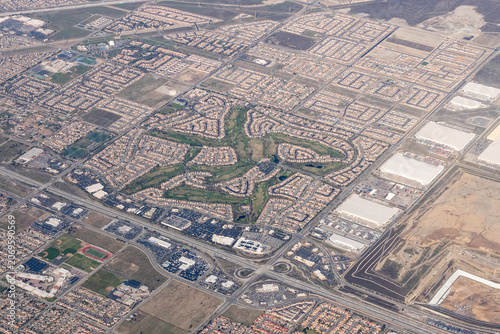 Aerial view of the Summit Lakes neighborhood and golf course surrounded by suburban development, warehouses, and AB Miller High School in Fontana, California, USA.
