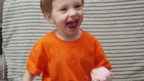 Child Eating, cupcake for dessert, sweet treat or sugar snack . Boy Bite, tasting vanilla cake with pink cream on top, hungry and enjoy delicious food. Happy childhood: a child enjoys a sweet treat