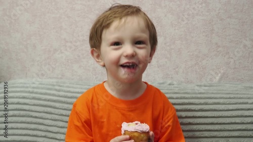 Child Eating, cupcake for dessert, sweet treat or sugar snack . Boy Bite, tasting vanilla cake with pink cream on top, hungry and enjoy delicious food. Happy childhood: a child enjoys a sweet treat