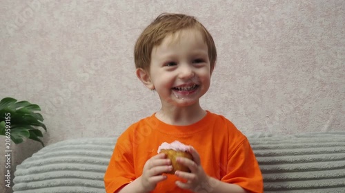 Child Eating, cupcake for dessert, sweet treat or sugar snack . Boy Bite, tasting vanilla cake with pink cream on top, hungry and enjoy delicious food. Happy childhood: a child enjoys a sweet treat