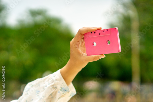 Hand holding a pink cassette. A tool for recording and storing music in the past.