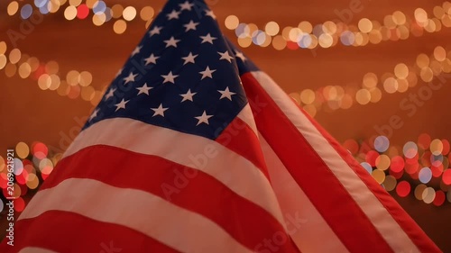 American flag waves proudly against a backdrop of warm, festive bokeh lights
