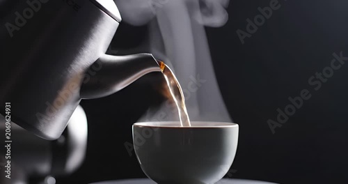 Steaming hot water pouring from kettle into cup on dark background, cozy aesthetic morning
