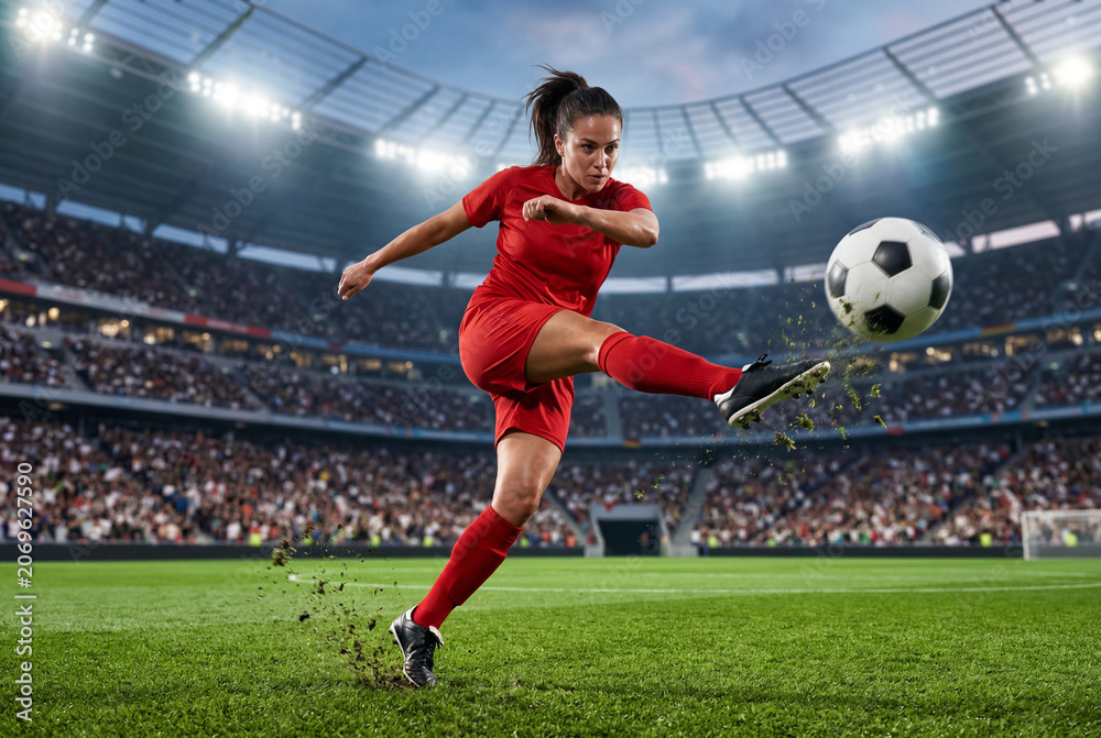 Naklejka premium Female athlete kicking soccer ball in stadium during match