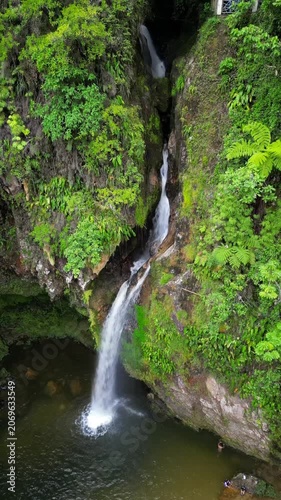 An breathtaking drone aerial shot showcasing the magnificent Breezes Waterfall in Cuetzalan, Puebla, Mexico. Lush green jungle surrounds the cascading water falling into a natural pool below.