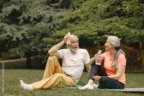 Senior couple sitting on exercise mats at park and talking