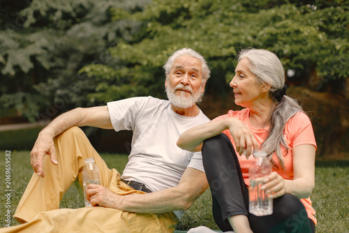 Senior couple sitting on exercise mats at park and talking