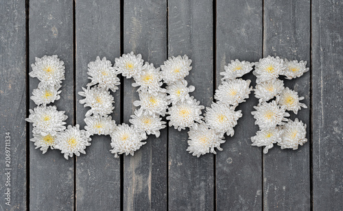 Word Love from White Flowers on Wooden Planks Surface. File with Clipping Path.