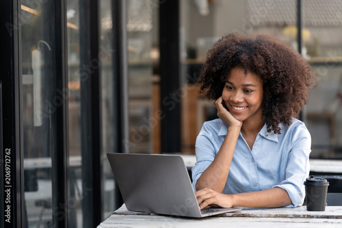 Smiling young African American woman working on laptop at outdoor cafe