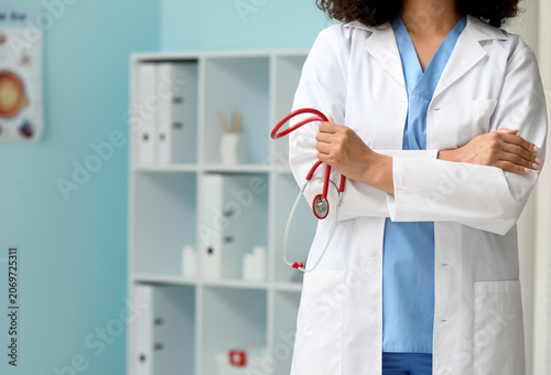 Beautiful young African-American female doctor with stethoscope in clinic, cl...