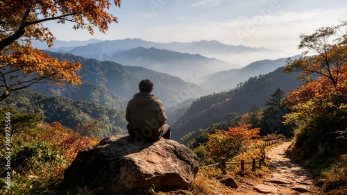 Man sitting on rock looking at scenic autumn mountain view for mindfulness meditation and wellness website banner