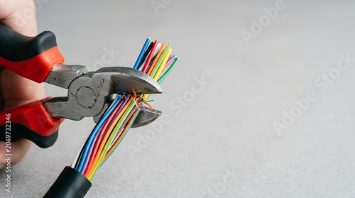 Wire cutters slicing through a bundle of colorful electrical cables
