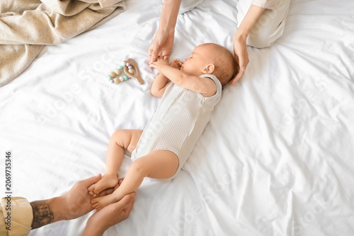 Young parents with their little baby sleeping on bed, top view