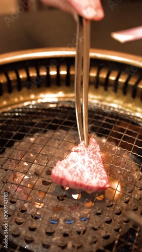 Raw Wagyu Beef Placed on Hot Charcoal Grill with Tongs