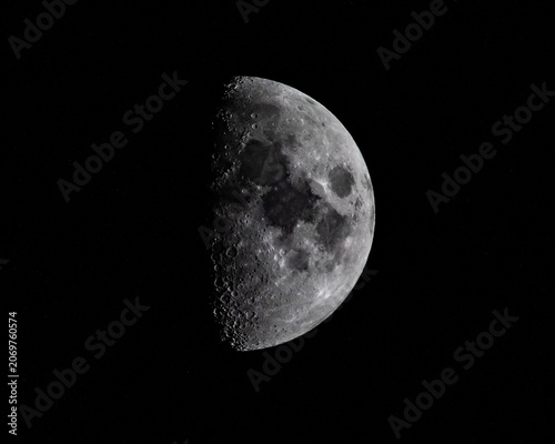 A half moon in a deep black sky with dramatic sunlight
