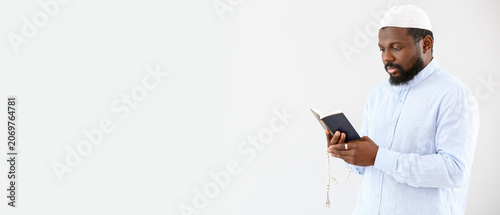 Foto African-American Muslim man with Koran and beads on light background