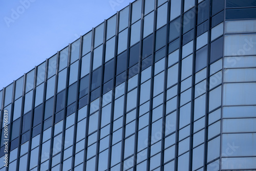 A section of a modern building with many rectangular glass windows reflecting the clear
