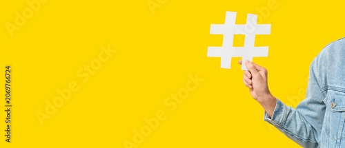 Fotografie Hand of young man with hashtag symbol on yellow background