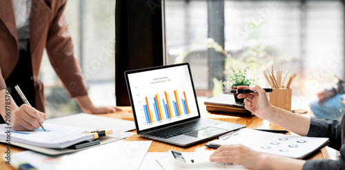 Close up of business people analyzing financial charts on laptop in office