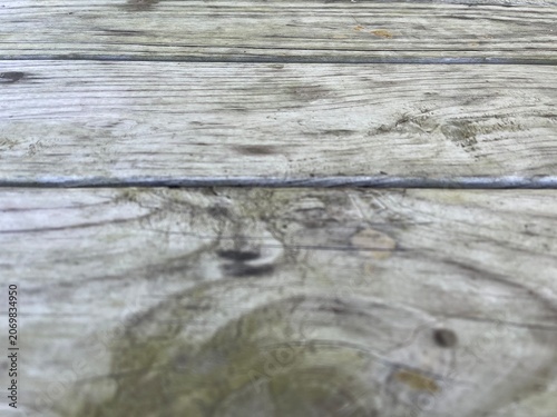 Rustic grey wood table with selective focus background. Abstract horizontal light gray wood texture background with copy space. Rustic empty wooden table top background with blurred foreground.