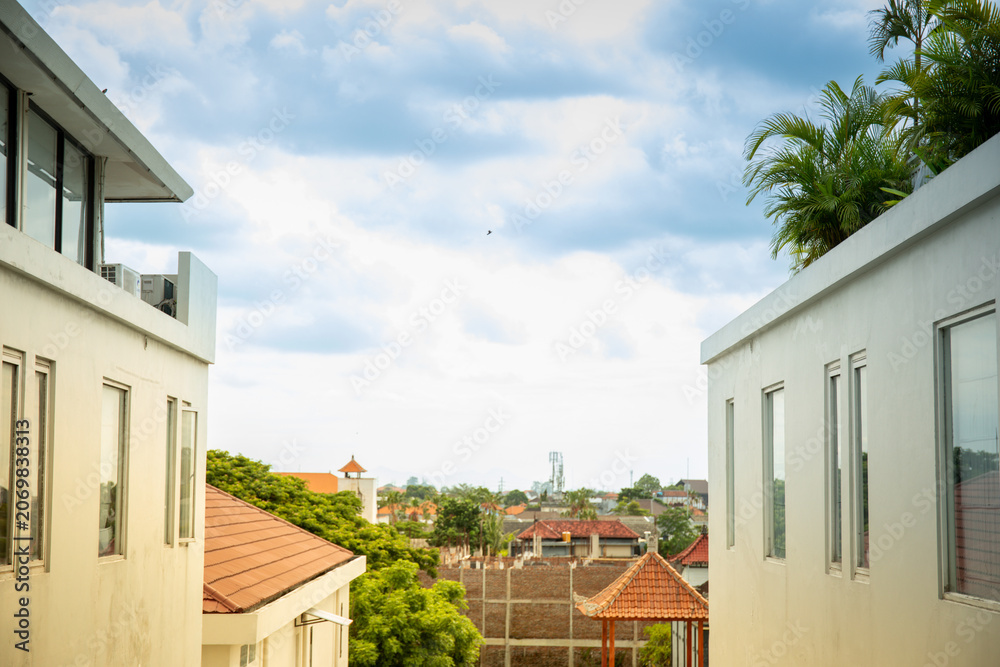 Fototapeta premium View from between buildings showing rooftops and clouds