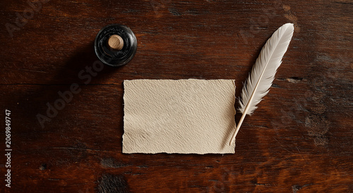 a overhead view of a textured, cream colored, rectangular piece of paper with deckle edges, positioned in the middle of a dark wood surface