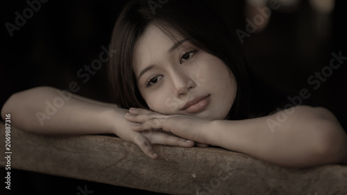 Young Woman Resting Chin On Hands With A Thoughtful Expression In A Serene Indoor Portrait
