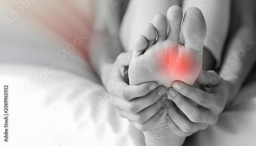 Severe foot sole pain with glowing red inflammation zone. Plantar fasciitis symptom and medical diagnosis. Close up view of hands holding a sore painful foot sole