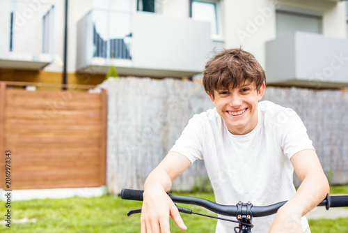 Photography Happy teenage boy with bicycle in yard on sunny day smiling and looking at camera outdoors