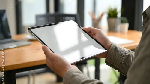 A close up view of professional hands holding a modern tablet device with a blank white screen area.