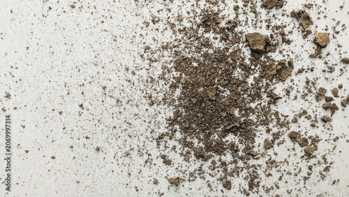Top view of crushed soil pile and dry dirt clumps scattered on white backdrop.