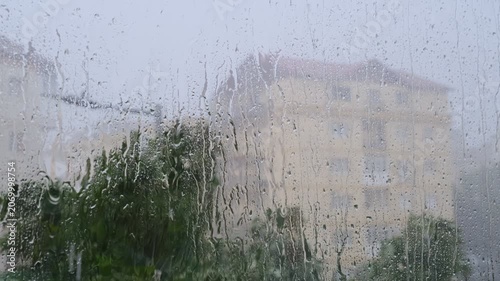 Heavy summer rain outside. Strong wind and rain drops falling on glass window