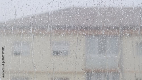 Heavy summer rain outside. Strong wind and rain drops falling on glass window
