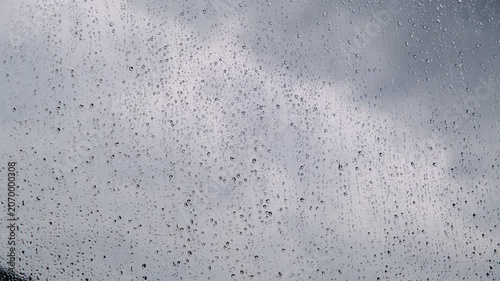 Heavy summer rain outside. Strong wind and rain drops falling on glass window