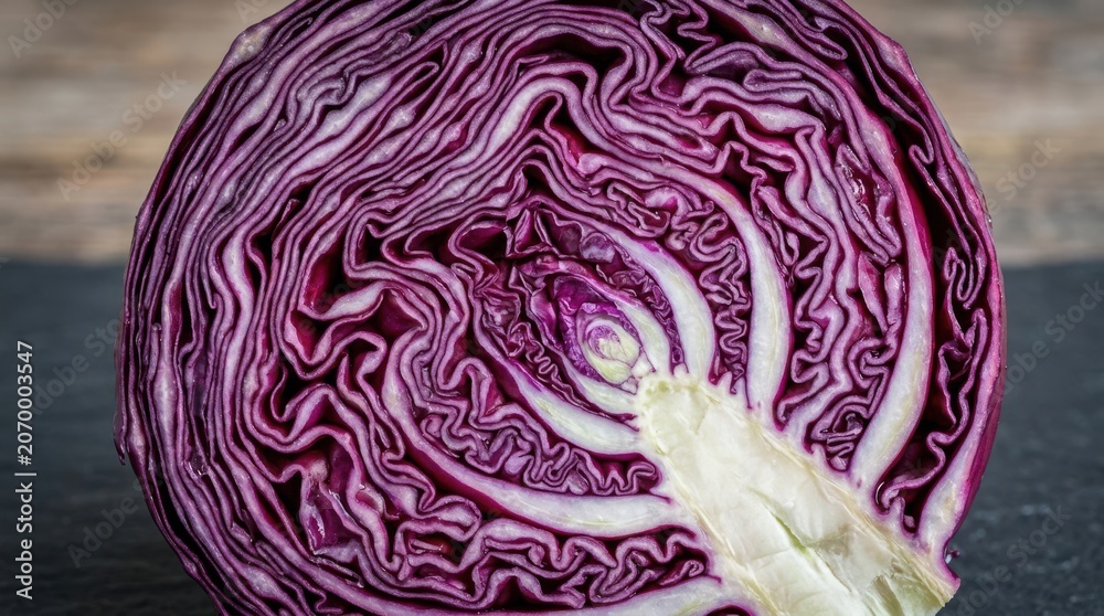 Obraz premium Cross section of fresh red cabbage head on dark background, macro shot of raw purple vegetable layers, healthy plant based diet ingredient for culinary photography