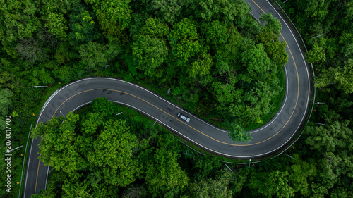 Aerial view mountain curve road in green forest, Mountain forest road surrounds natural forest, Winding road through lush green forest road tree.