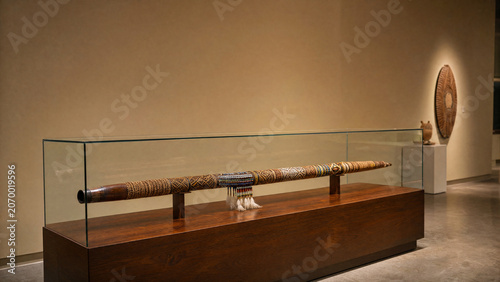 An ornate ceremonial blowpipe displayed in a museum case.