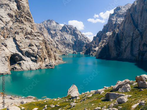 Aerial view of the turquoise waters of Kol-Suu lake nestled between steep limestone cliffs and rugged mountain peaks in At-Bashi District, Naryn Region, Kyrgyzstan.