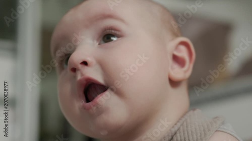 Teething baby lying down, chewing toy and moving hands and feet actively. Top view of sweet infant crying and smiling during first teeth growth milestone. Pediatric and parenting concept.