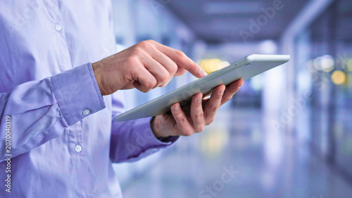 Close-up of a professional's hands actively engaging with a sleek digital tablet, symbolizing efficient modern workflow and advanced technology utilization in a dynamic business environment