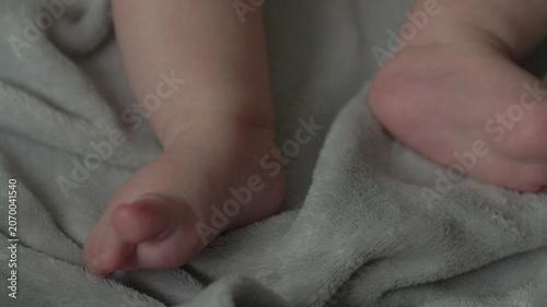 Teething baby lying down, chewing toy and moving hands and feet actively. Top view of sweet infant crying and smiling during first teeth growth milestone. Pediatric and parenting concept.