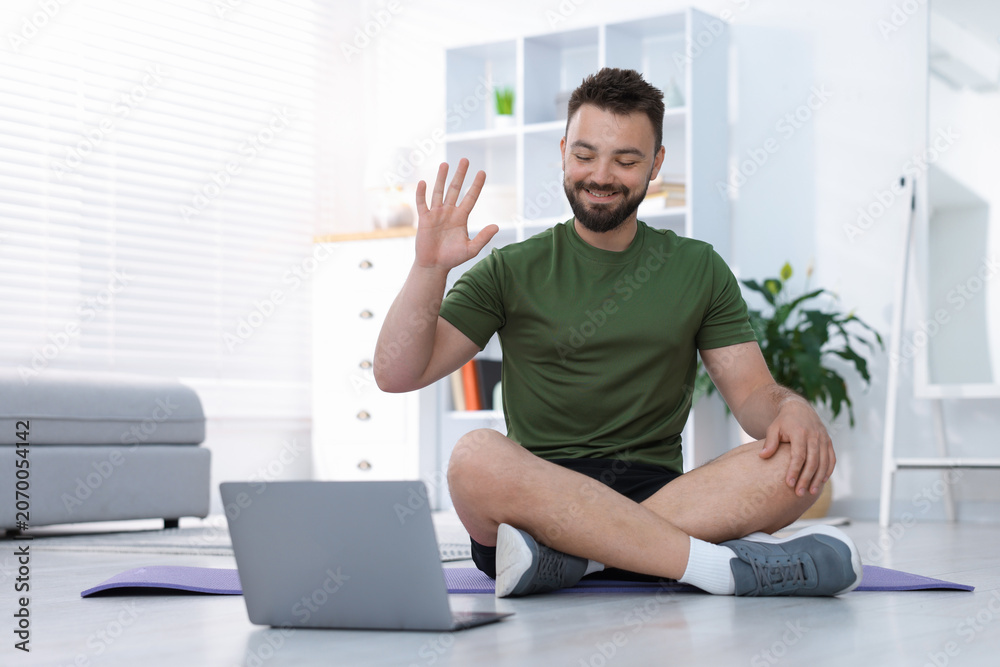 Fototapeta premium Online fitness trainer. Man watching tutorial on laptop at home
