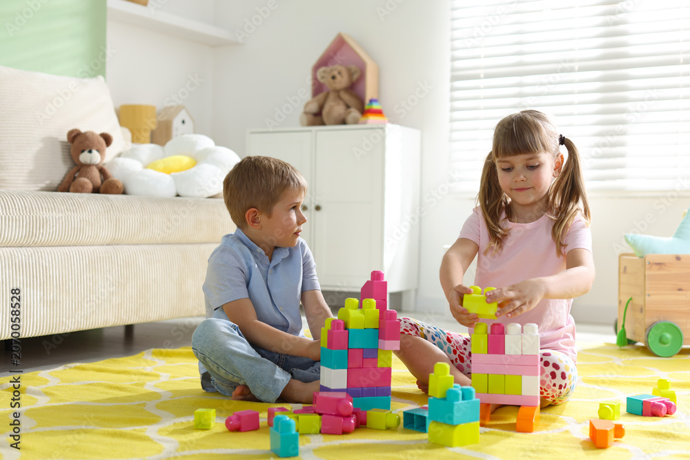 Obraz premium Little kids playing with colorful blocks on floor at home