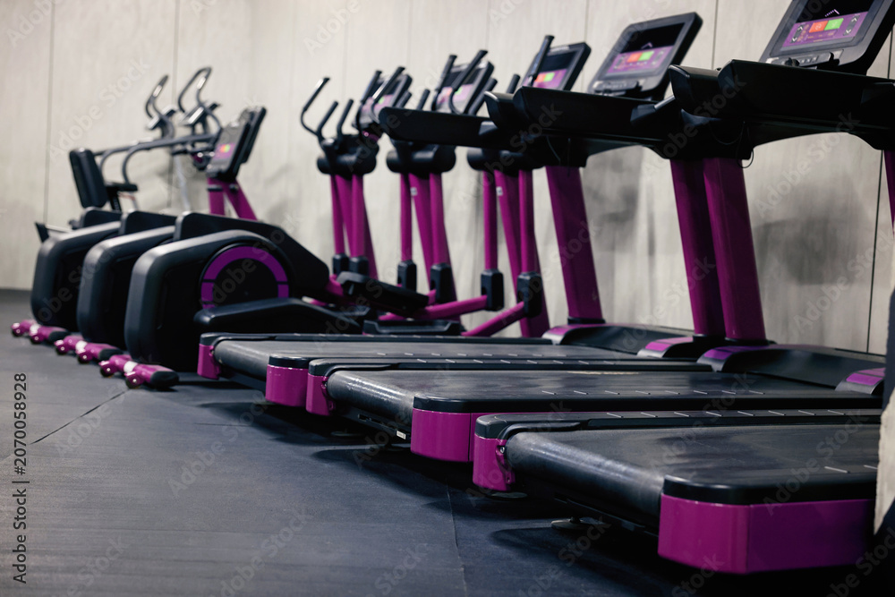 Obraz premium Gym cardio zone with exercise bikes and treadmills, selective focus