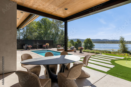 Modern home patio overlooking a pool and river, with putting green